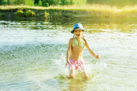 Happy child splashes water in a pondの写真素材