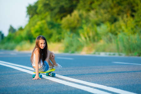 A young girl with penny board outside the city at the road.の写真素材