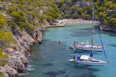    Crowded Beach With Tourists and Yachts at the Beautiful Bay of Cala Pi  