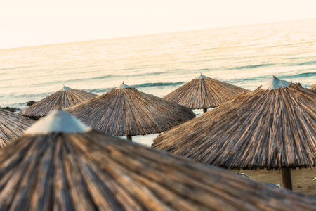 Beautiful Sandy Beach with Straw Umbrellas at Sunrise in Georgioupolis, Island of Crete, Greeceの写真素材