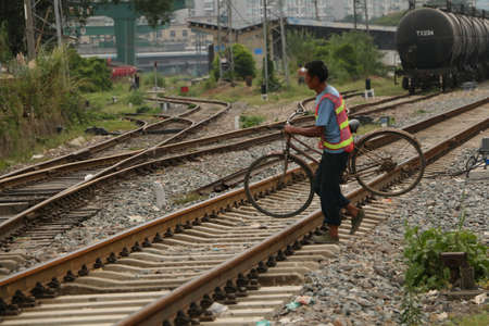 A man carrying a bicycle across the railroadのeditorial素材