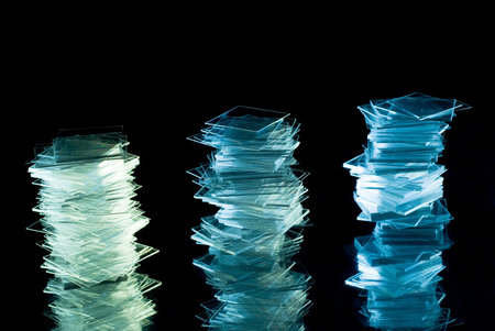 Glass stacks on reflective surface isolated on blackの写真素材