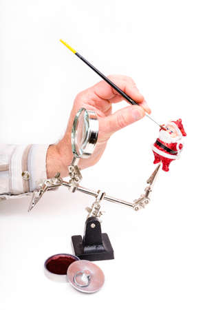 Hand hold brush and paints on a Christmas decoration located in holderの写真素材