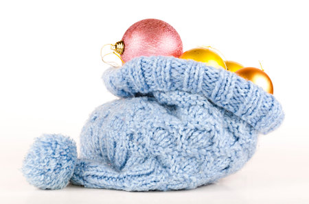 Christmas balls in knitted hat on white background