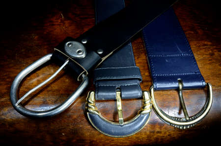 Close up of belts with buckles on the mahogany tableの写真素材