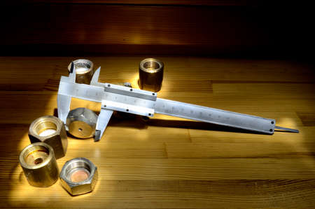 Caliper and brass nuts on wooden tabletopの写真素材