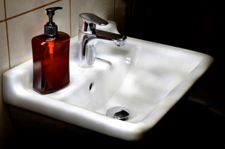 Contemporary bathroom basin with bottle of liquid soap の写真素材