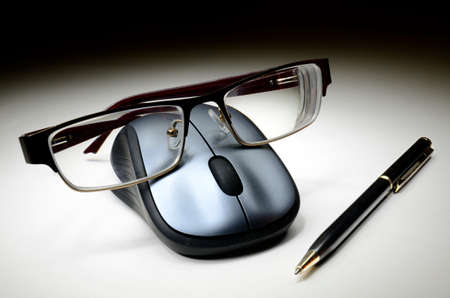 Computer mouse with glasses and pen on tableの写真素材