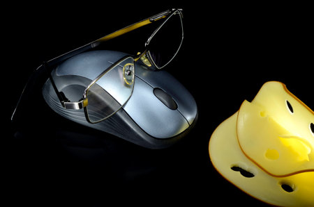 Computer mouse with glasses and cheese on black backgroundの写真素材