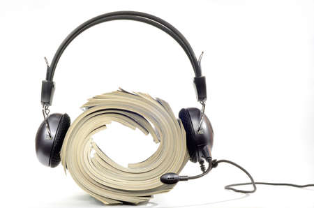 Headphones with microphone worn by stacked magazines on white backgroundの写真素材