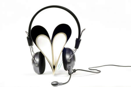 Headphones with microphone worn by magazine in heart shape on white backgroundの写真素材