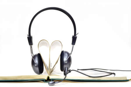 Headphones with microphone worn by pages curled into heart shape on white backgroundの写真素材