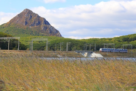  locomotive on  railway among wood and mountainsの写真素材