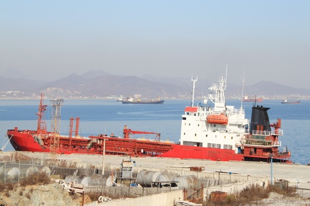 Red tanker standing at  old mooring against  ships on raidの写真素材