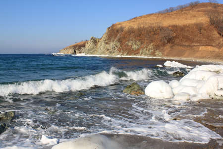 Ice covered stones on  seashore against  clear skyの写真素材