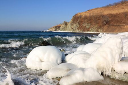 Ice covered stones on  seashore against  clear skyの写真素材