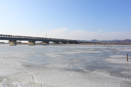 Winter landscape with bridge through  river covered  iceの写真素材