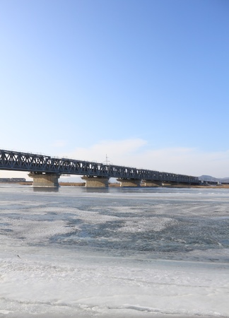 Winter landscape with bridge through  river covered  iceの写真素材