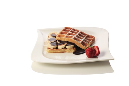 Waffles with bananas, strawberry and chocolate syrup, strawberries. Isolated on white background.の写真素材