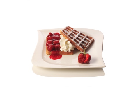 Waffles with strawberries and syrup, topped with whipped cream. Isolated on white background.の写真素材