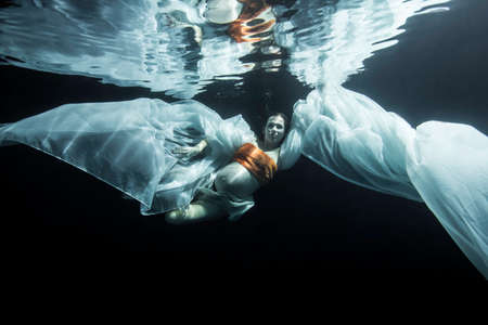 Pregnant woman swimming underwaterの写真素材
