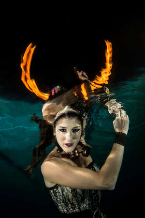 Girl posing underwater with fire Loks like a hornの写真素材