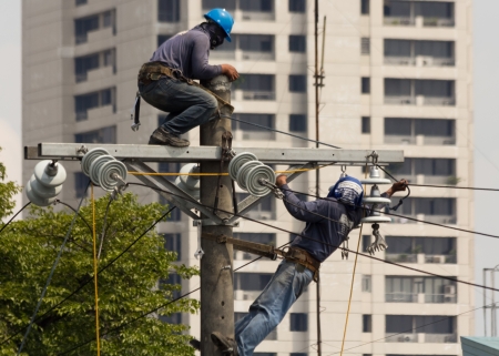 Quezon City, Philippines - June 8, 2013: Electricians installing new high voltage electrical concrete post inside the Philippine National Police- Head Quarters in Camp Crame.のeditorial素材
