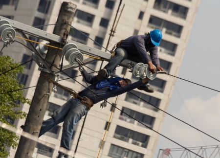 Quezon City, Philippines - June 8, 2013: Electricians installing new high voltage electrical concrete post inside the Philippine National Police- Head Quarters in Camp Crame.のeditorial素材