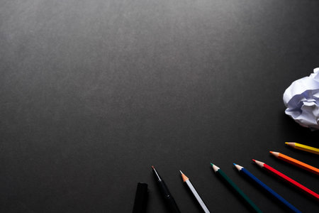 Top view of color pencil, pencil, black magic pen, crumpled paper and black backgroundの写真素材