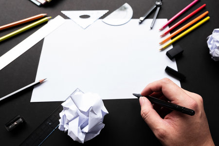 Empty white sheet of paper with sketching tools and man hand holding a black magic pen.の写真素材