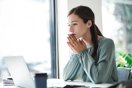Young confident businesswoman sitting at the office table focused working on laptop computer.の写真素材