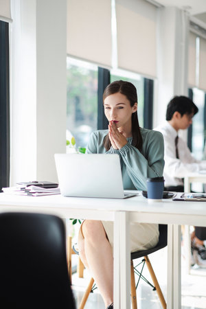 Vertical image of young and beautiful businesswoman tired from work in the office.の写真素材