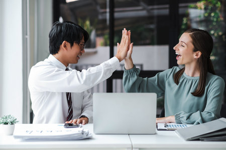 Business people celebrate with laptop success happy pose. E-commerce, internet technology, or startup small business concept. Modern office.の写真素材