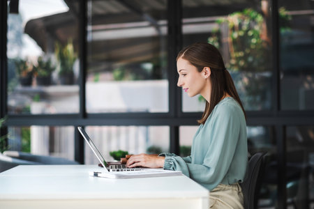 Young confident businesswoman sitting at the office table working on laptop computer..の写真素材