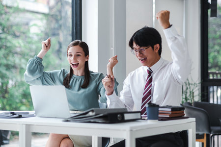 Business people celebrate with laptop success happy pose. E-commerce, internet technology, or startup small business concept. Modern office.の写真素材