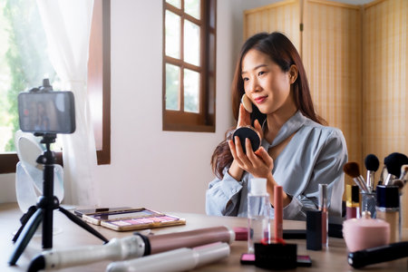Beauty blogger, asian young woman, girl vlogger makeup face, showing, reviews cosmetics products while recording video, tutorial to share on social media. Business online influencer on smartphone.の写真素材