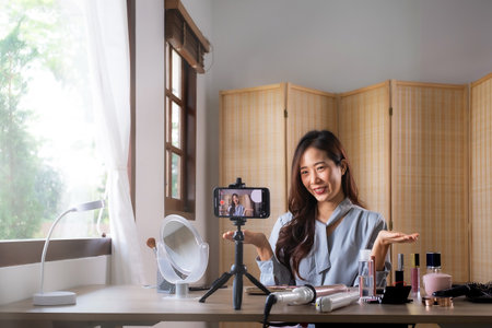 Beauty blogger, young asian woman, girl vlogger speaking, showing, reviews cosmetics products while recording video, tutorial to share on social media. Business online influencer on smartphoneの写真素材