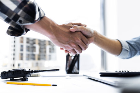 Image of engineer dealings or shaking hand for architectural project. working with laptop and engineering tools on workplace.の写真素材