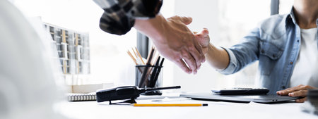 Image of engineer dealings or shaking hand for architectural project. working with laptop and engineering tools on workplace.for banner design.の写真素材