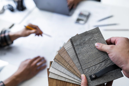 Close up of engineer hands holding wooden floor samples and meeting for architectural project. working with partner and engineering tools on workplace.の写真素材