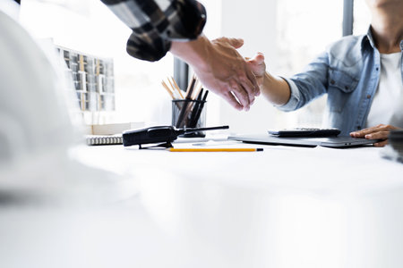 Image of engineer dealings or shaking hand for architectural project. working with laptop and engineering tools on workplace.の写真素材