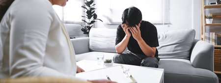 Psychologist sitting and touch hand young depressed asian man for encouragement, PTSD Mental health concept, For banner design.の写真素材