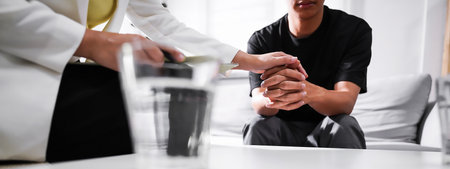 Psychologist sitting and touch hand young depressed asian man for encouragement, PTSD Mental health concept. For banner design.の写真素材