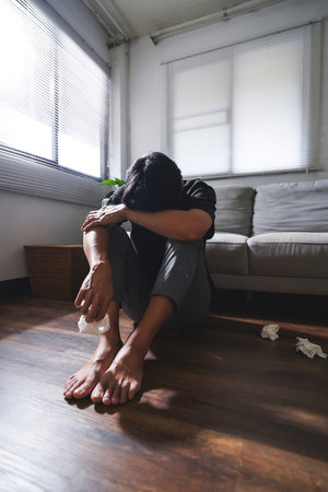 Asian man with depression sitting alone on the floor.の写真素材