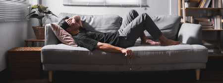 Stressed man lying on sofa holding glasses for relax. For banner design.の写真素材