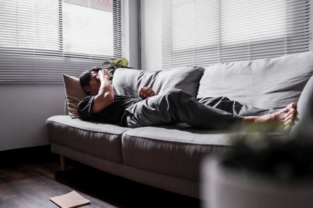 Stressed man lying on sofa holding glasses.の写真素材