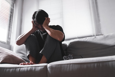 Close up of asian man with depression sitting alone on sofa.の写真素材