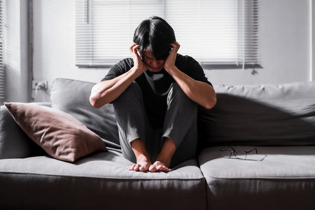 Close up of asian man with depression sitting alone on sofa.の写真素材