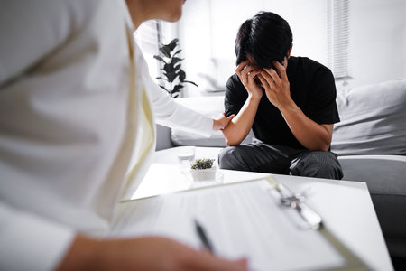 Psychologist sitting and touch hand young depressed asian man for encouragement, PTSD Mental health concept.の写真素材