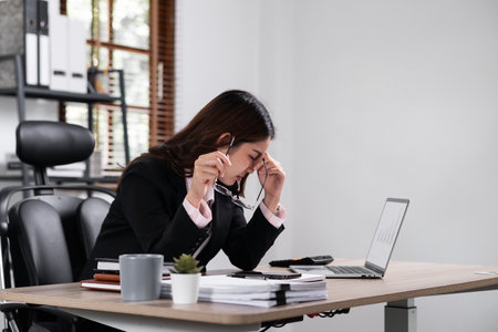 Business woman are stressed while working on laptop, Tired asian businesswoman with headache at office, feeling sick at work.の写真素材